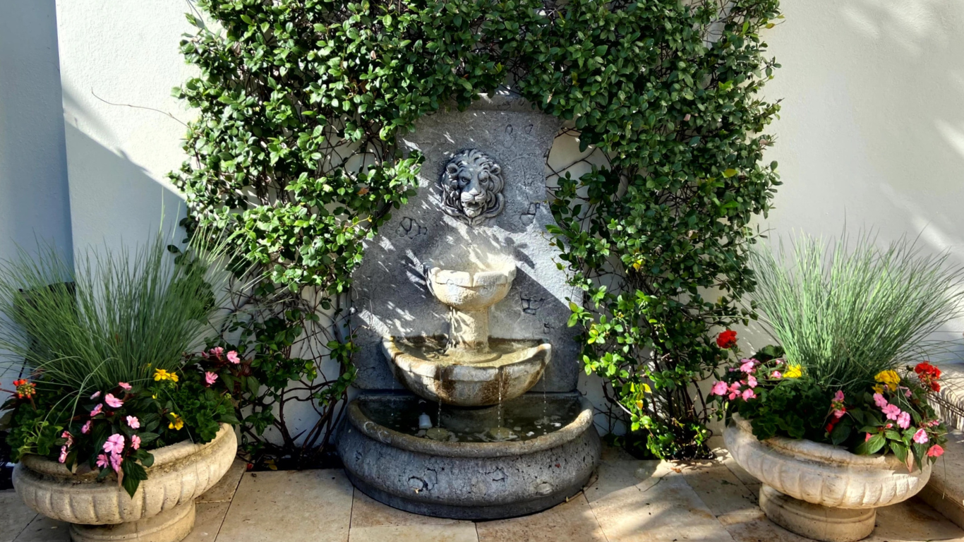 A lush courtyard filled with vibrant courtyard container gardens, brick walkways, and climbing greenery surrounding a historic stone building.