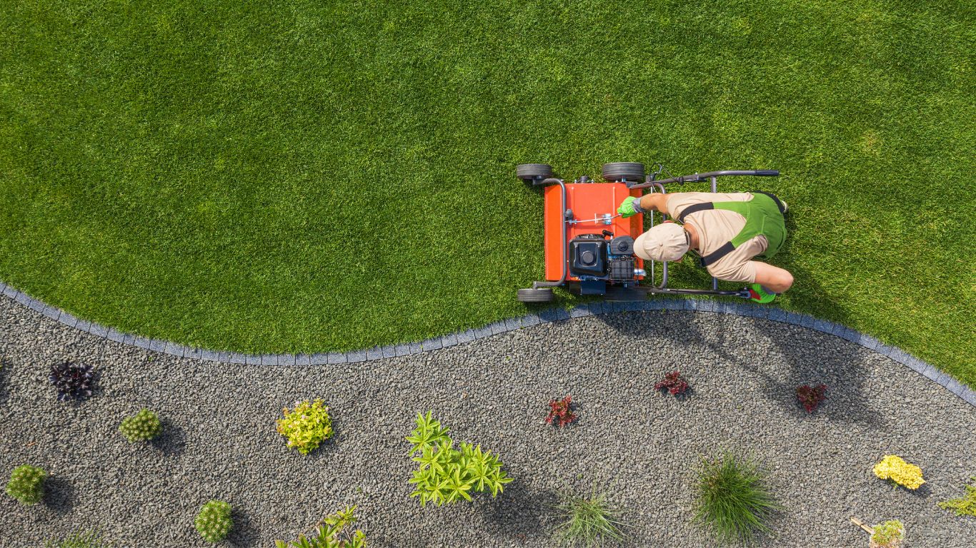 Lawn maintenance with a worker mowing a well-kept lawn.